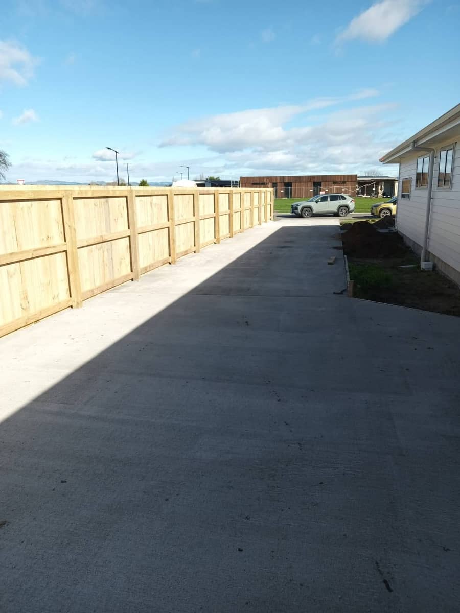 Broom-finished concrete driveway alongside a timber fence in Gisborne