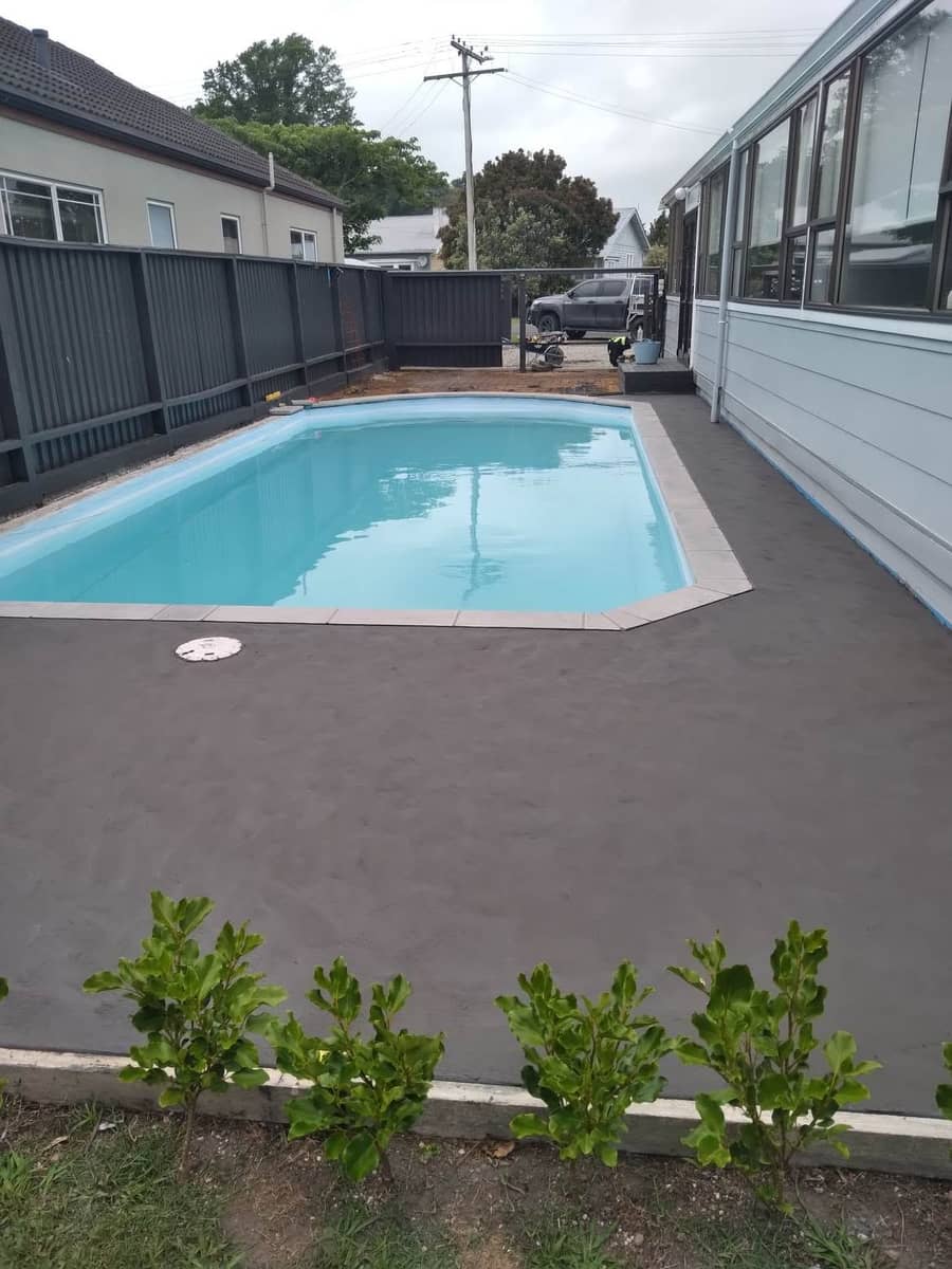 Coloured concrete pool surround with tiled coping in Gisborne by Eastcrete Solutions